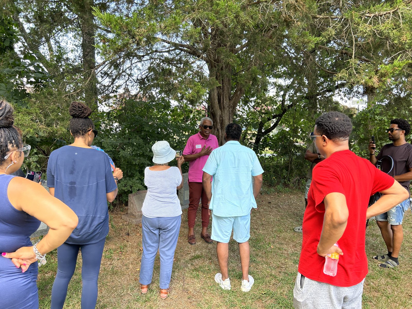Family group listening to a talk near trees